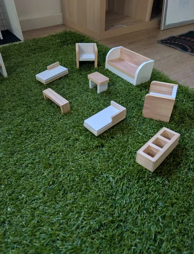 Wooden doll's house furniture set out on grass mat for small world play at Lakeside Creative Minds