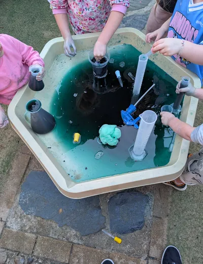 Children's hands exploring coloured water with measuring tubes at Lakeside Creative Minds